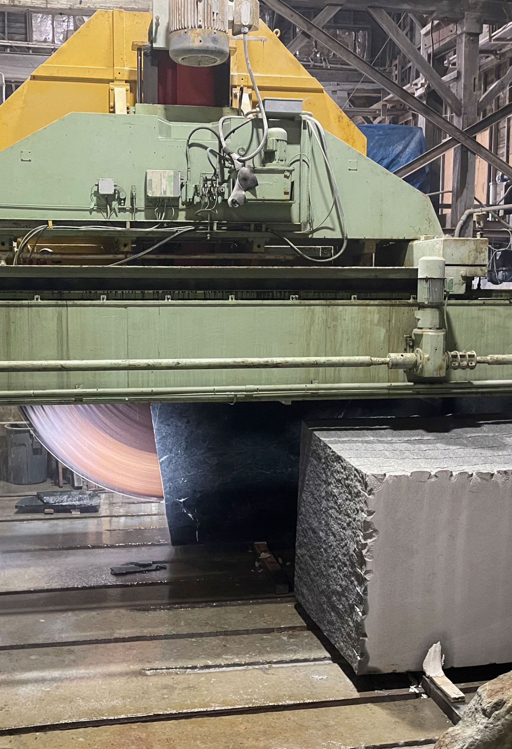 Massive circular wet saw cuts block of Vermont Verde Serpentine green marble into slabs of varying thickness.